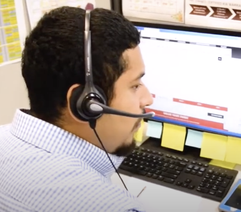 Man on phone headset in working environment looking at laptop screen showing call tracking analytics.
