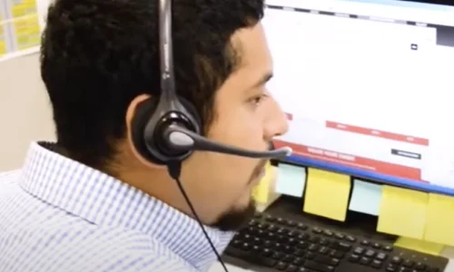 Man on phone headset in working environment looking at laptop screen showing call tracking analytics.