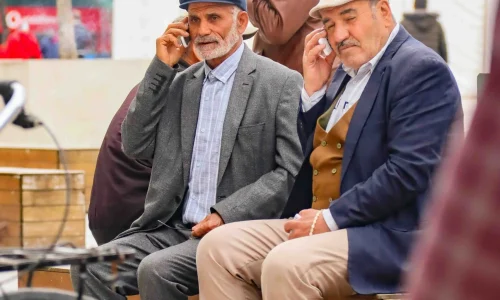 elderly people sitting outside making a call