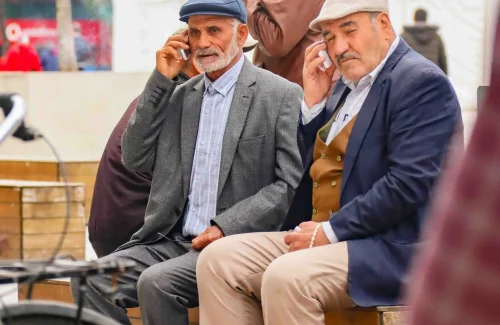 elderly people sitting outside making a call
