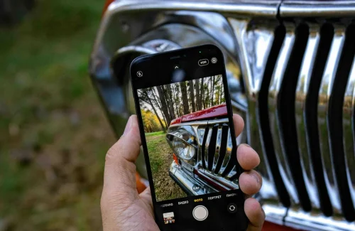 man holding a phone in his hand and taking a picture of a car