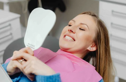 woman looking at her teeth in the mirror in a dental office