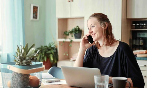 woman holding a phone with laptop