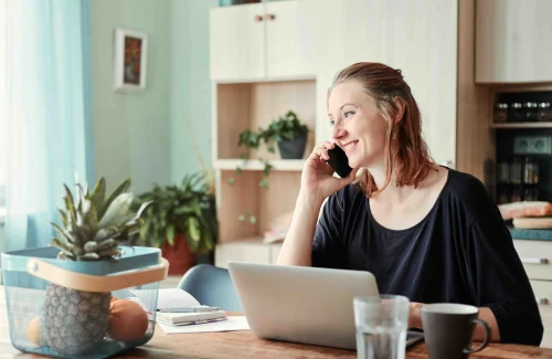 woman holding a phone with laptop